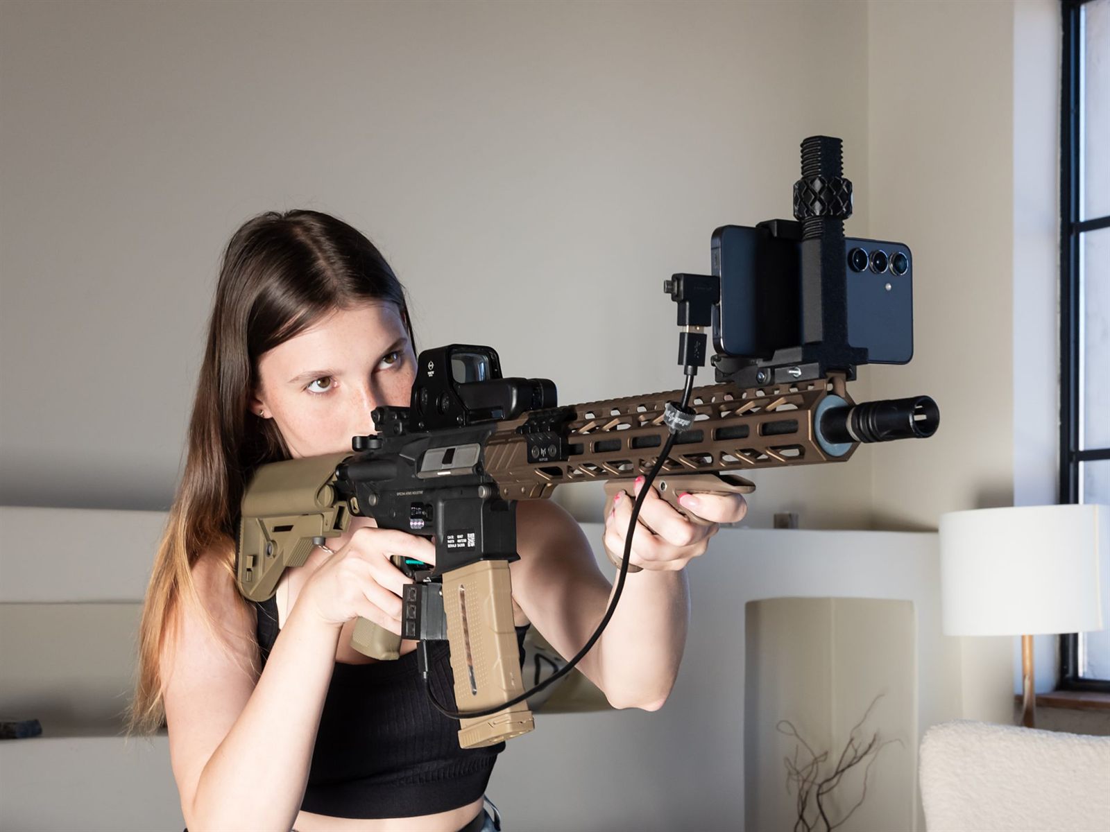 A training platform with a phone held above the handguard by an ORiQ mount, aimed indoors.